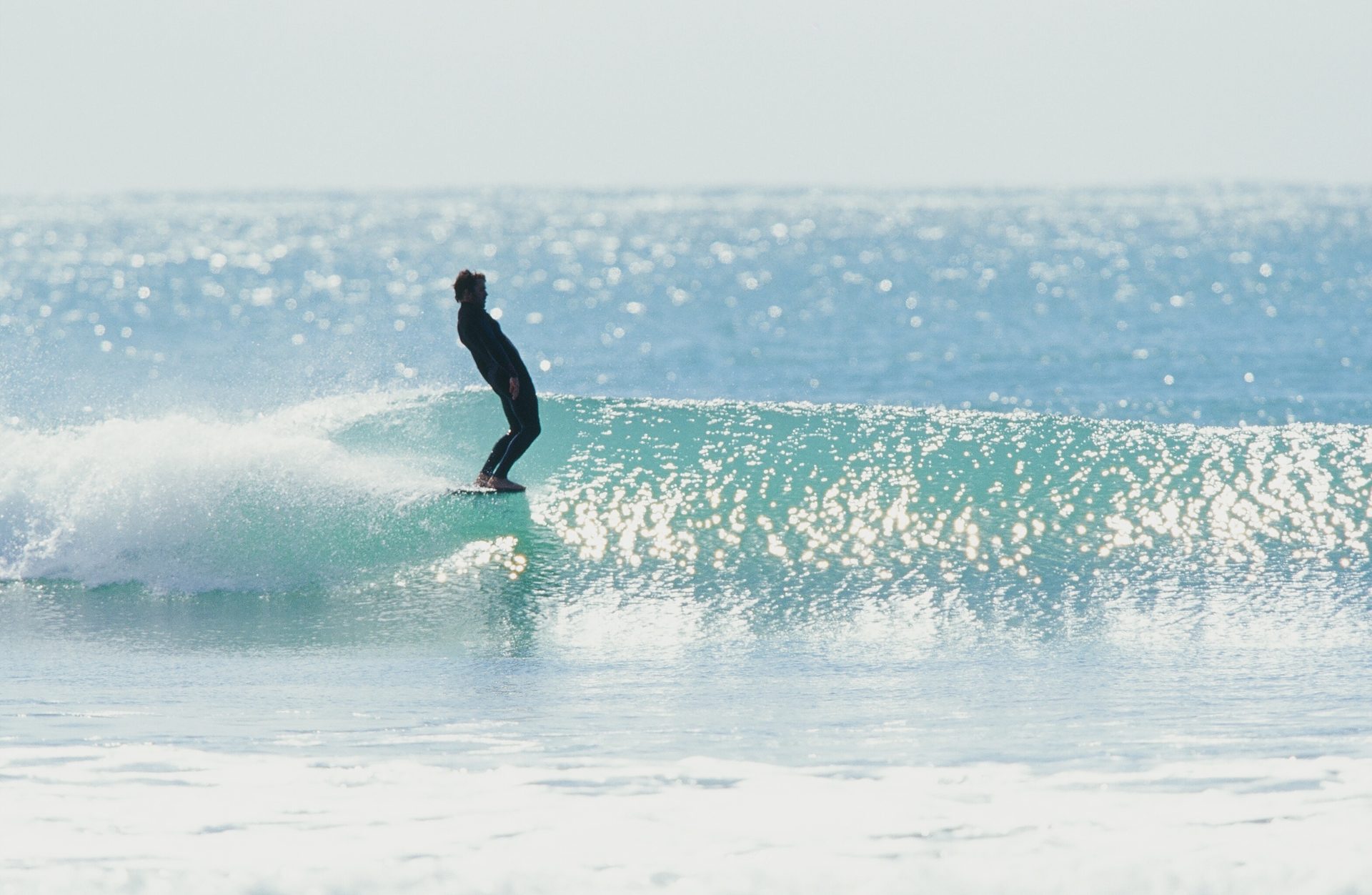 CJ Nelson surfing a backlit, sparkling wave