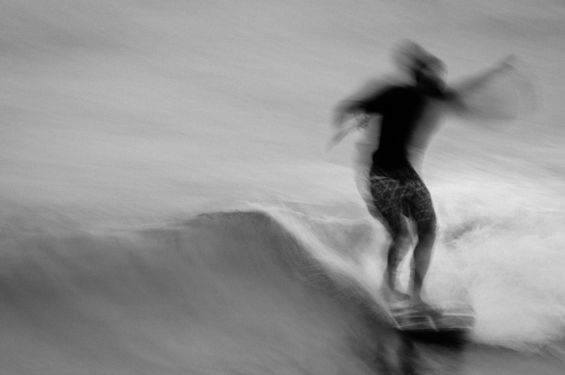 Blurred black-and-white frame of a surfer in motion