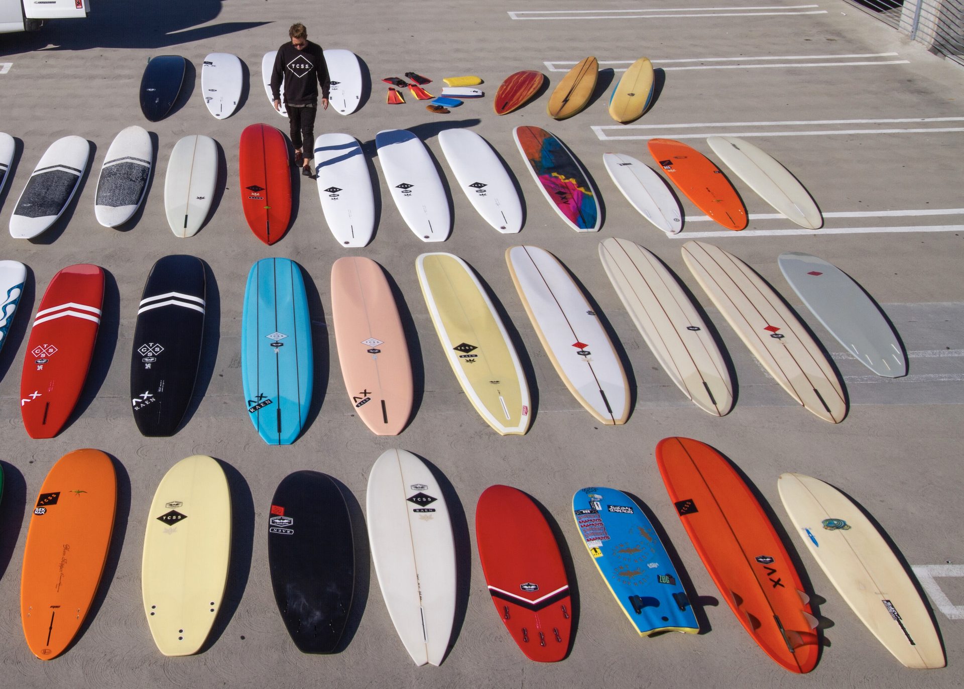 A quiver of surfboards laid out in rows, seen from above